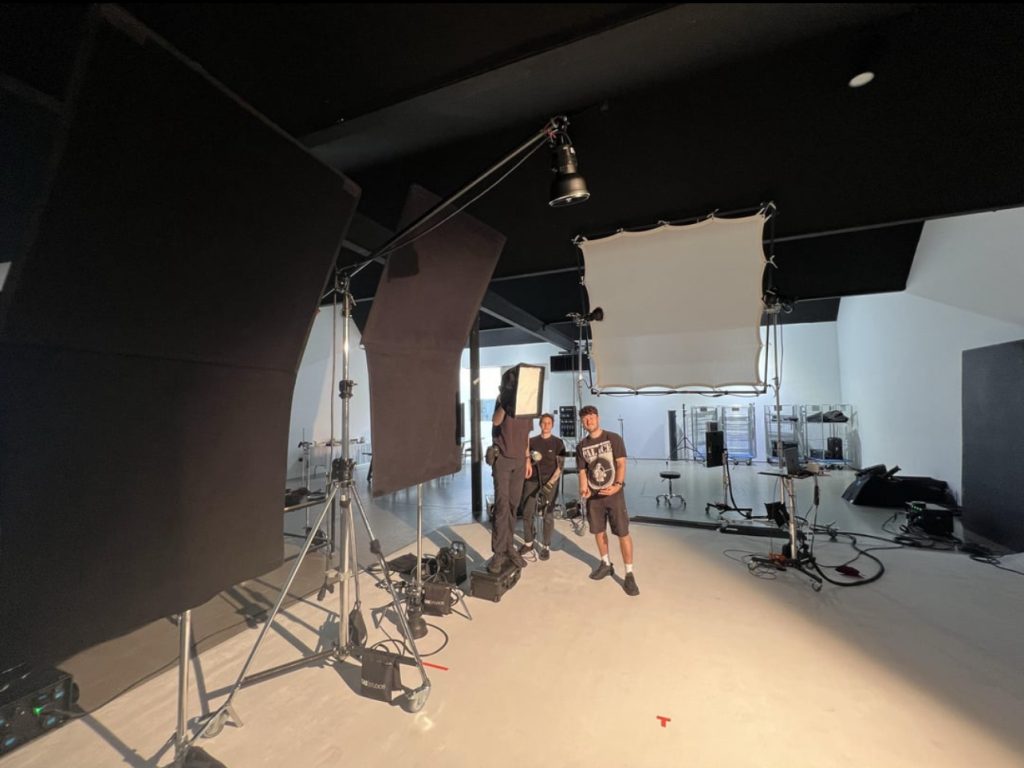 An image of a photography studio, with photography lights being shown. The studio is white and black with an angled ceiling.